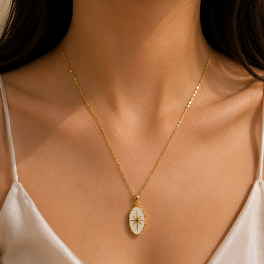 Gold necklace with a star pendant on a person wearing a white top.