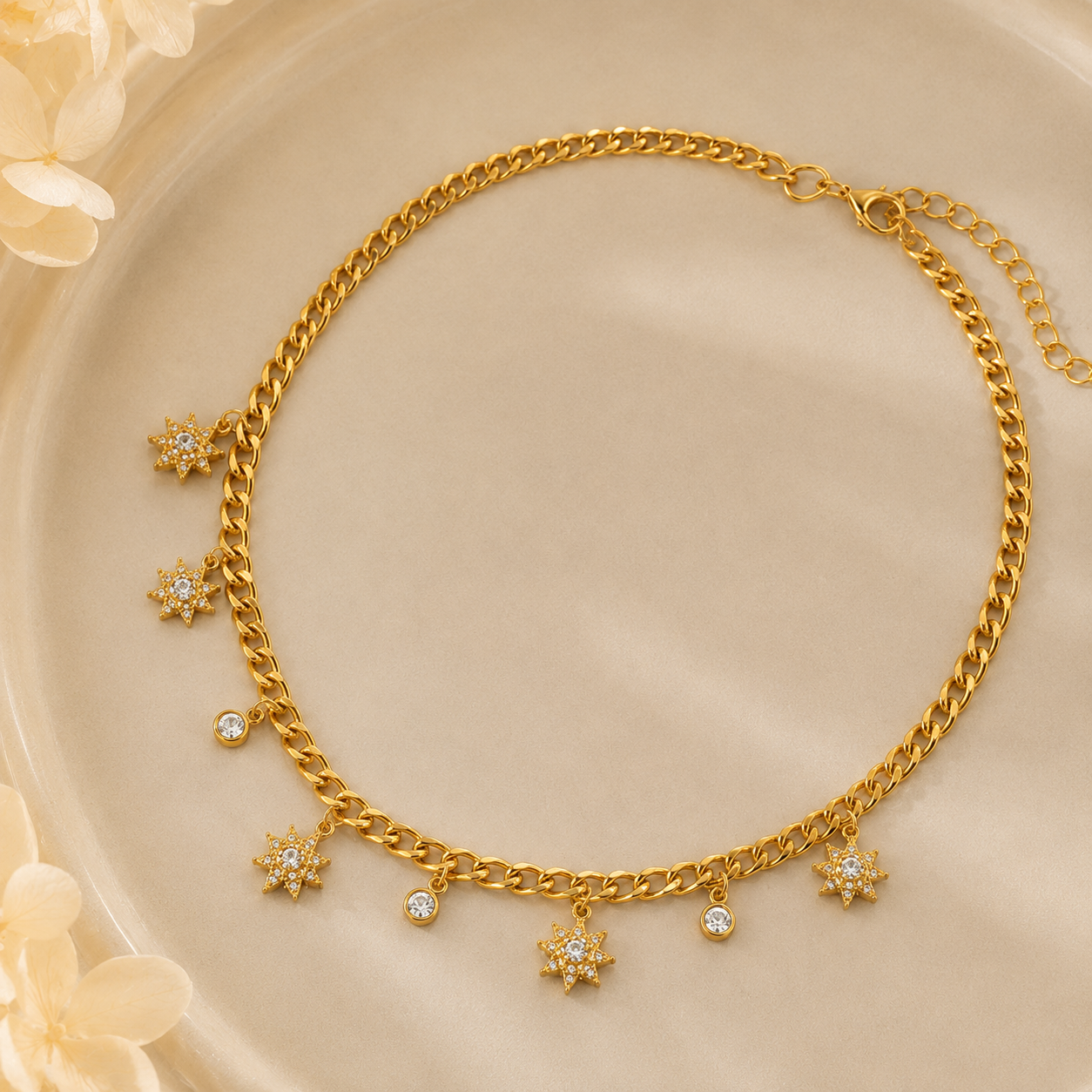 Gold necklace with star-shaped charms on a beige background