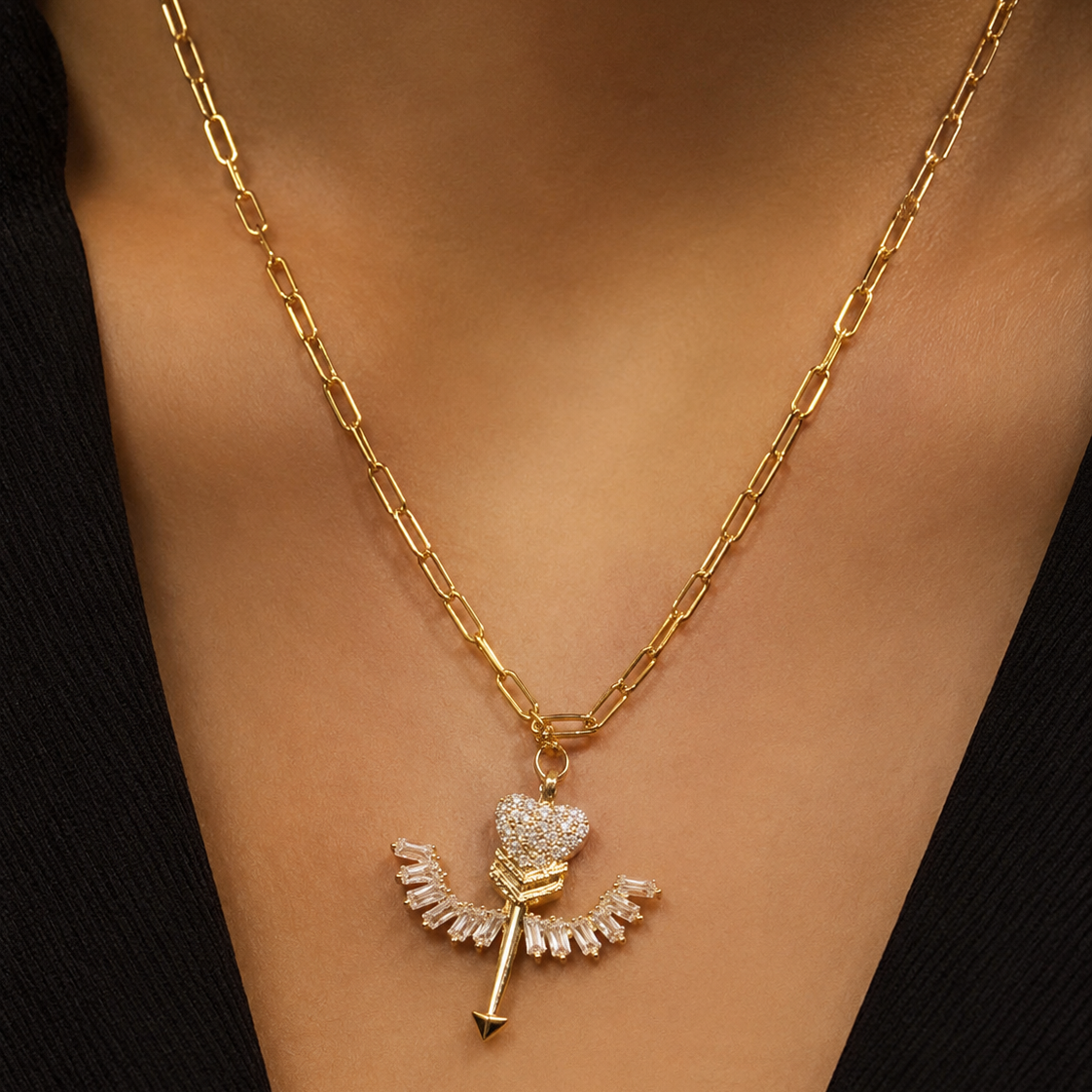 Gold necklace with a heart-shaped pendant on a person's neck