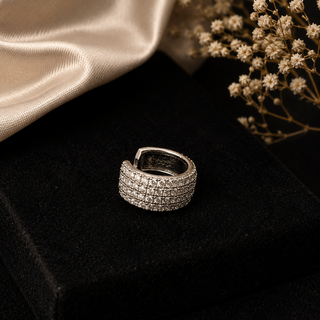 Silver ring with multiple bands on a dark surface with a beige fabric and dried flowers in the background