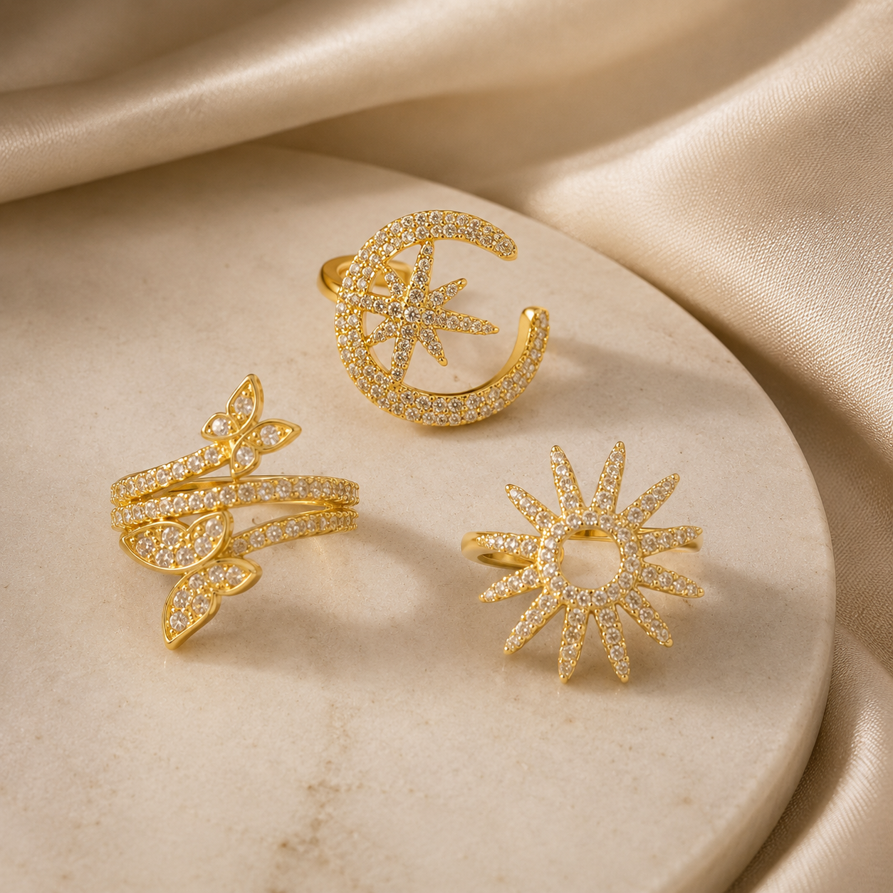 Three gold rings with different designs on a beige marble surface.