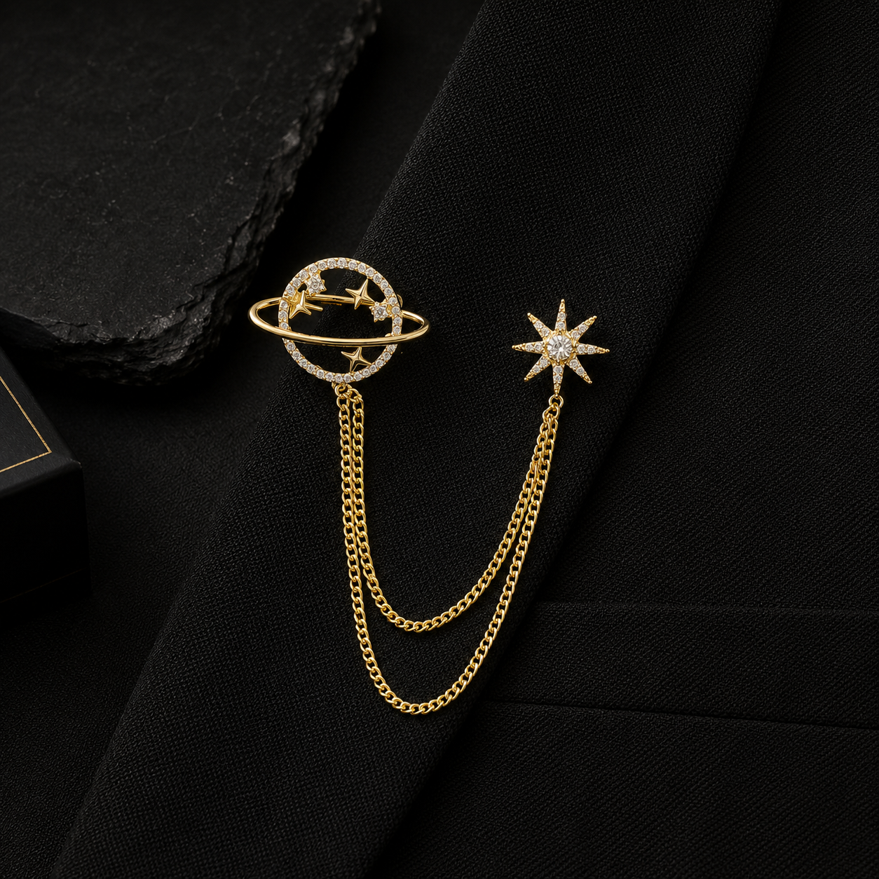 Gold chain earring with celestial design on a black fabric background