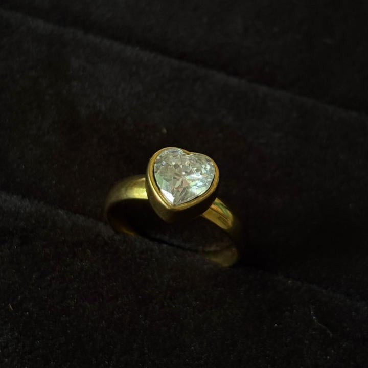 Gold ring with a heart-shaped diamond on a black background