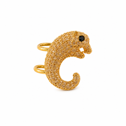 A gold ring shaped like a stylized lowercase letter c, encrusted with small clear stones and featuring a single black stone for the eye, shown on a plain white background.