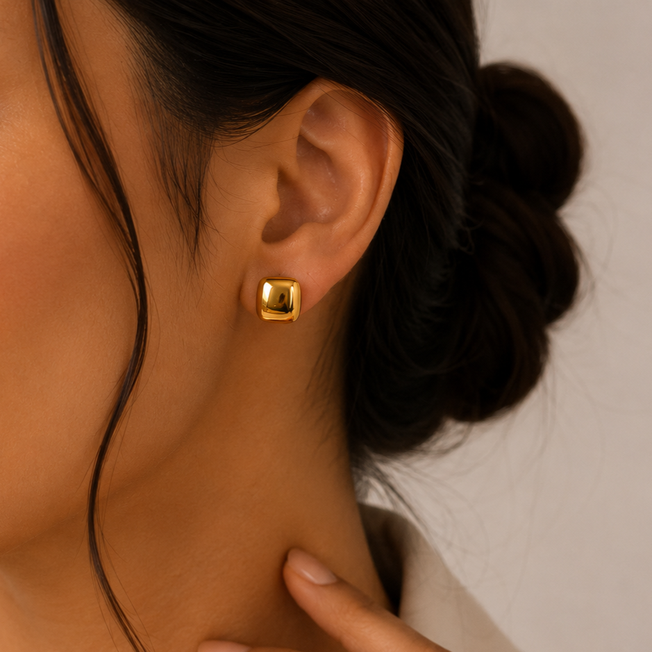 Close-up of a person wearing a gold earring with a blurred background