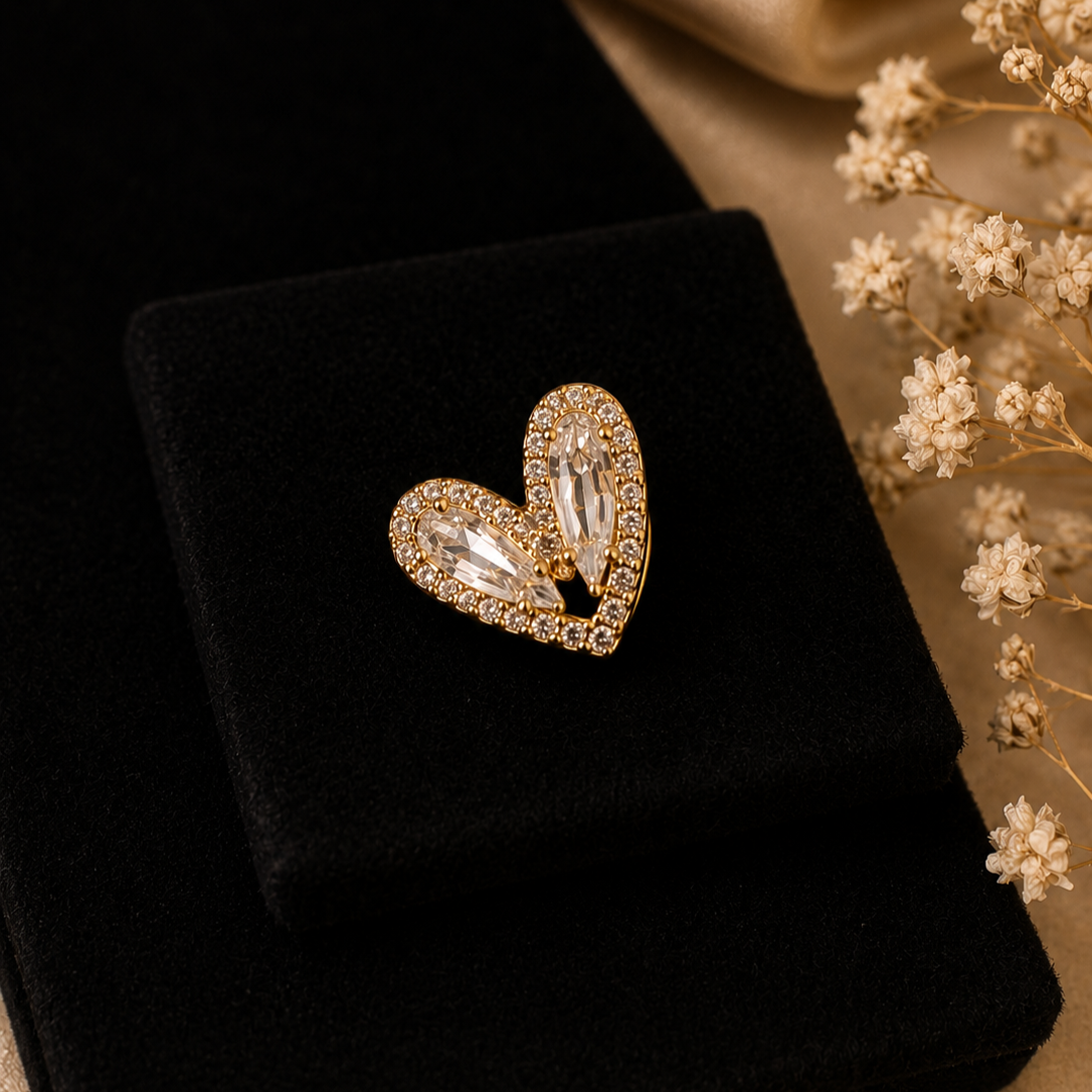 Gold heart-shaped earring on a black cushion with flowers in the background