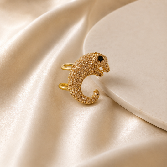 Gold animal-shaped ring on a beige satin surface