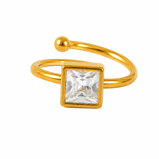 A gold-plated open band ring featuring a square bezel-set clear crystal gemstone, shown on a plain white background.