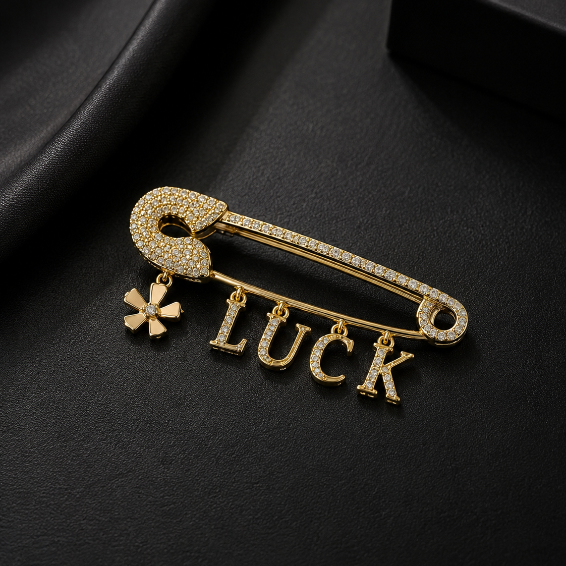 Gold brooch with 'LUCK' and clover charm on a black background