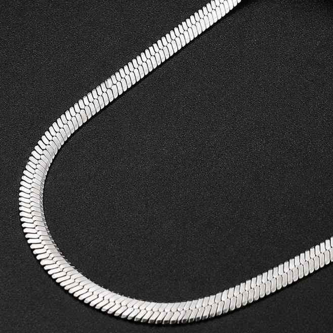 Close-up of a silver snake chain on a black background