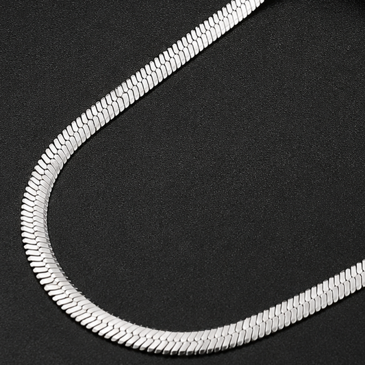 Close-up of a silver snake chain on a black background