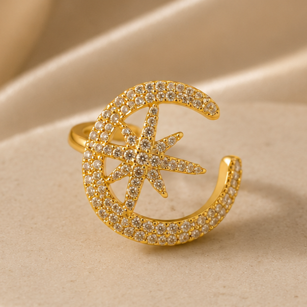 Gold ring with star and crescent design on a beige fabric background