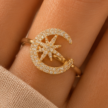 Gold ring with moon and star design on a person's finger