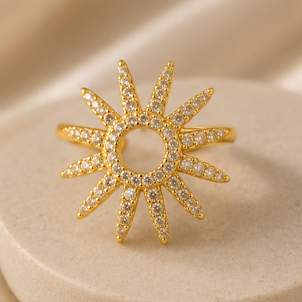 Gold sun-shaped ring with gemstones on a beige background