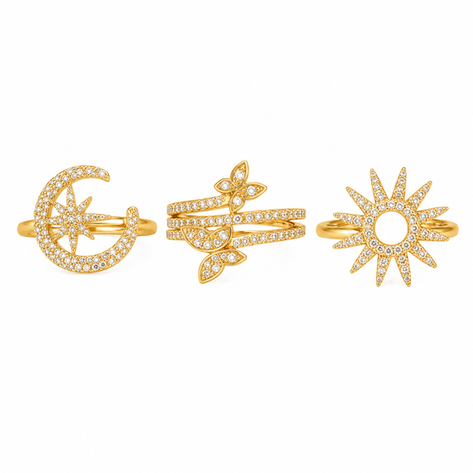 Three gold rings with pavé-set clear stones, featuring a crescent moon and star design, a leafy branch motif, and a sunburst design, displayed on a clean white background.