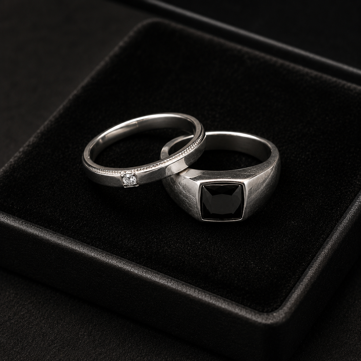 Two silver rings with gemstones on a black velvet surface