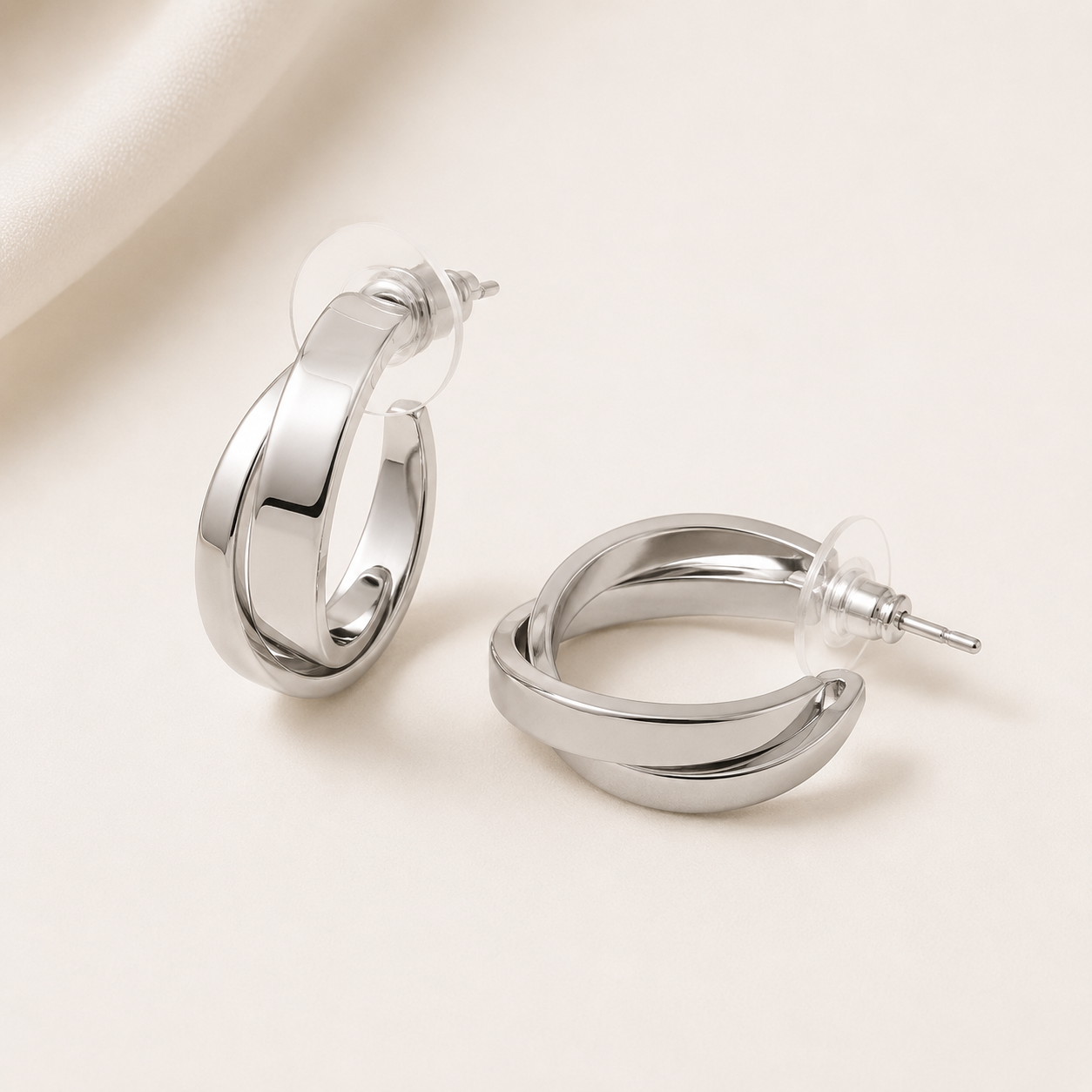 Pair of silver hoop earrings on a light beige background