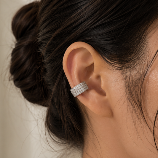 Close-up of an ear wearing a diamond earring with hair styled in a bun.
