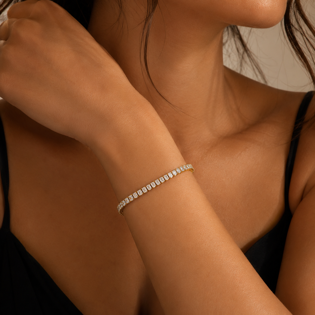 Close-up of a person wearing a diamond bracelet on a neutral background