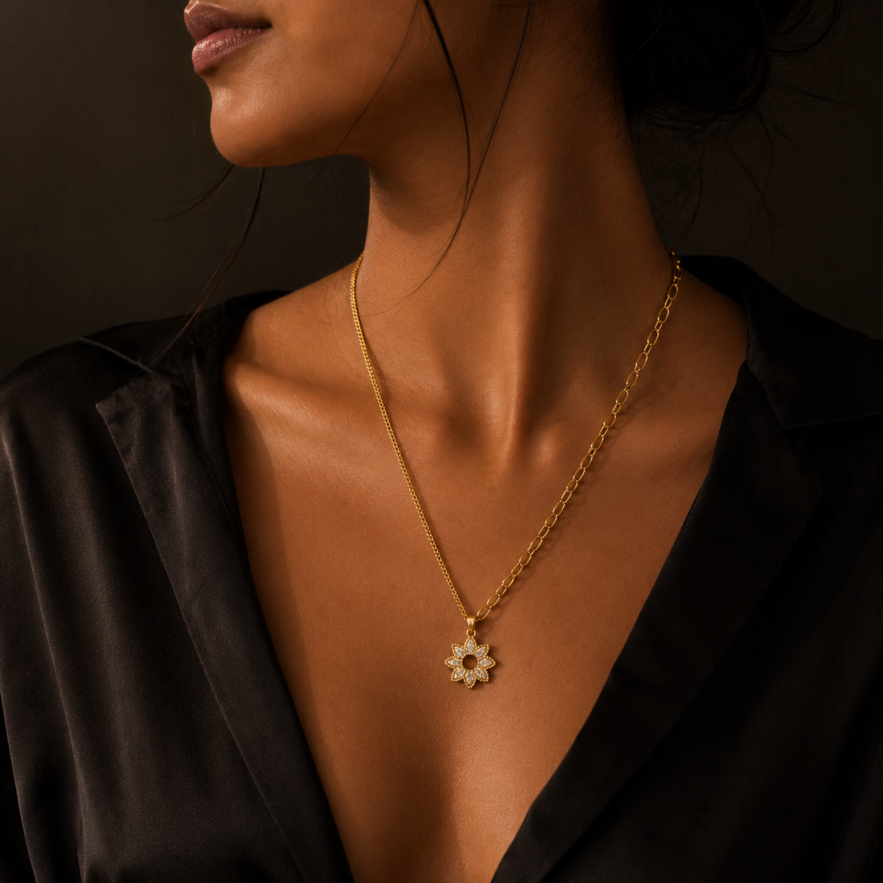 Close-up of a person wearing a gold necklace with a pendant against a dark background